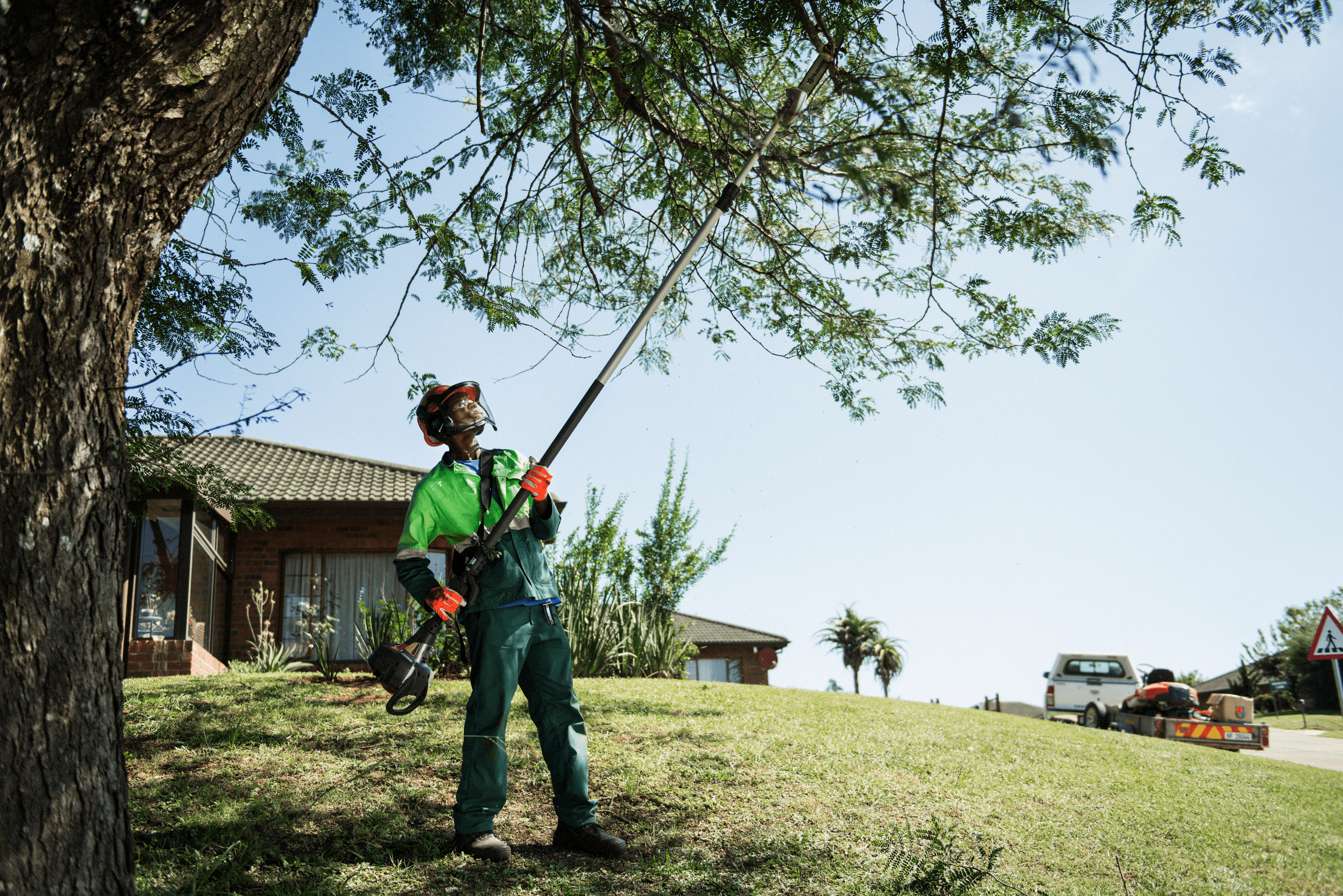 man holding polesaw whilst cutting tree